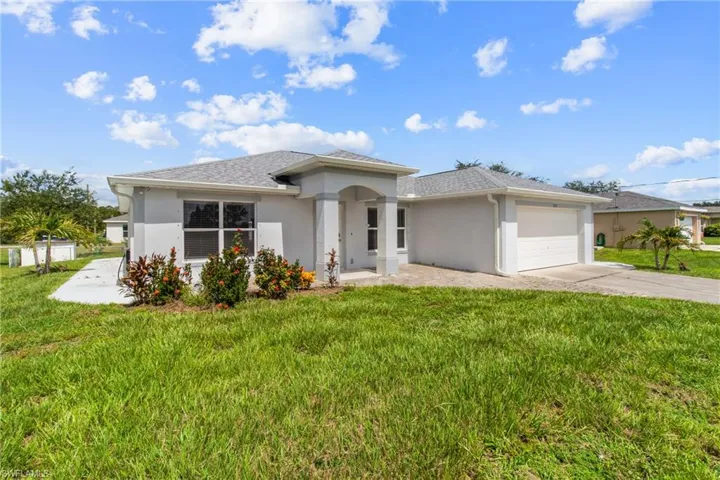 View of front of property featuring stucco siding, concrete driveway, a garage, and a front yard