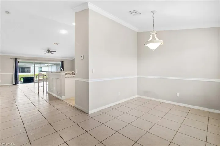 Empty room featuring crown molding, light tile patterned flooring, and ceiling fan