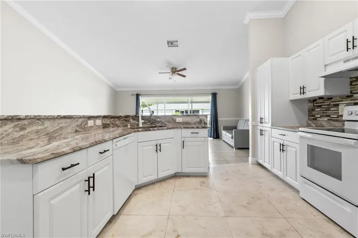 Kitchen featuring white appliances, crown molding, backsplash, a ceiling fan, and light stone countertops