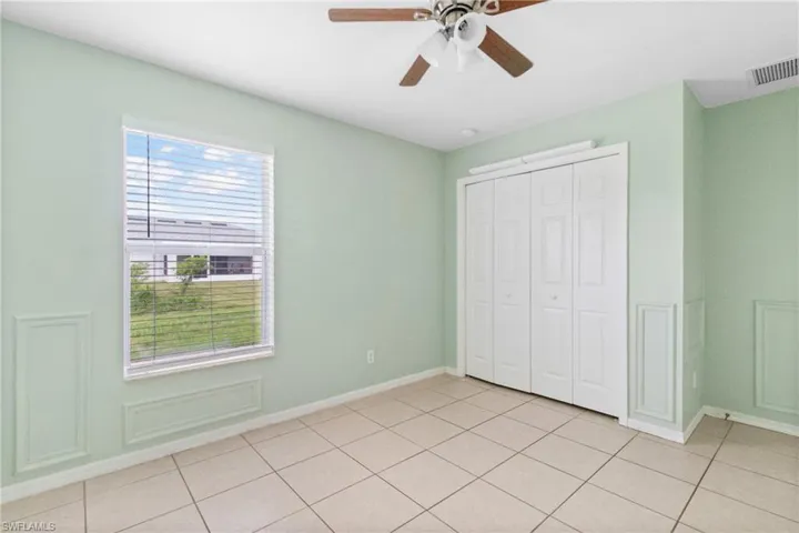 Unfurnished bedroom featuring a closet, light tile patterned floors, and a ceiling fan