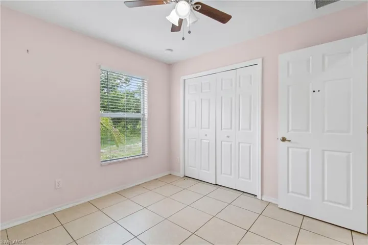 Unfurnished bedroom featuring a closet, light tile patterned floors, and ceiling fan