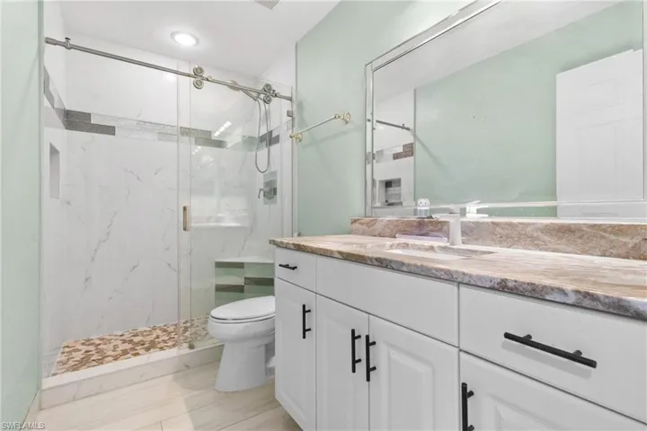 Full bath featuring a marble finish shower and vanity