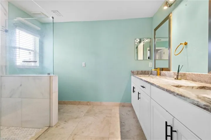 Bathroom featuring double vanity, a walk in shower, and tile patterned flooring