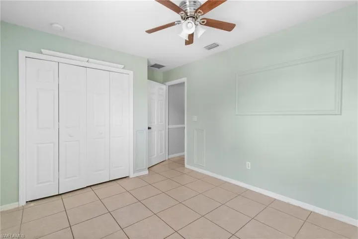 Unfurnished bedroom featuring a closet, light tile patterned flooring, and a ceiling fan