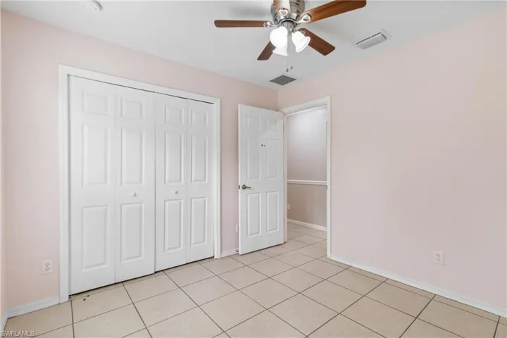 Unfurnished bedroom with a closet, light tile patterned floors, and a ceiling fan