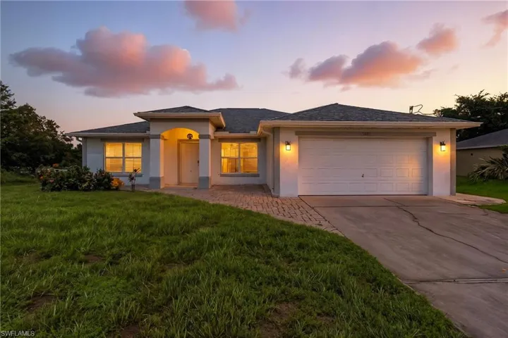 Prairie-style house featuring stucco siding, an attached garage, concrete driveway, a front yard, and roof with shingles