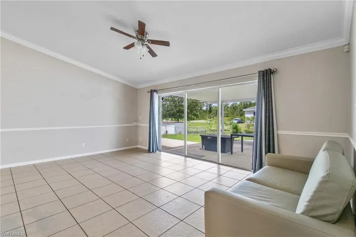 Unfurnished living room featuring a ceiling fan, ornamental molding, light tile patterned flooring, and vaulted ceiling