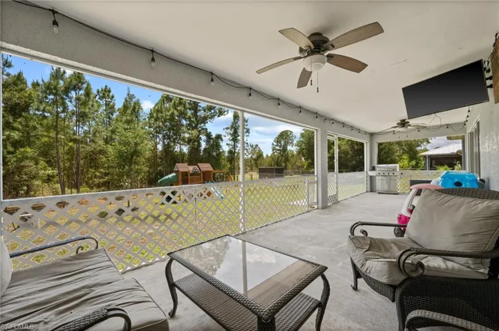Expansive outdoor patio featuring a concrete floor, multiple ceiling fans, and string lighting