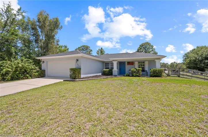 Single-story residence featuring a light-colored exterior, a prominent blue entry door, and a two-car garage