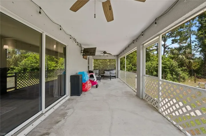 Expansive covered patio featuring a concrete floor, white lattice railing, and multiple ceiling fans