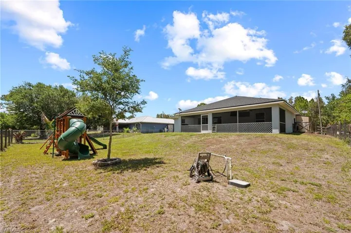 Expansive backyard featuring a screened-in patio, mature trees, and a privacy fence