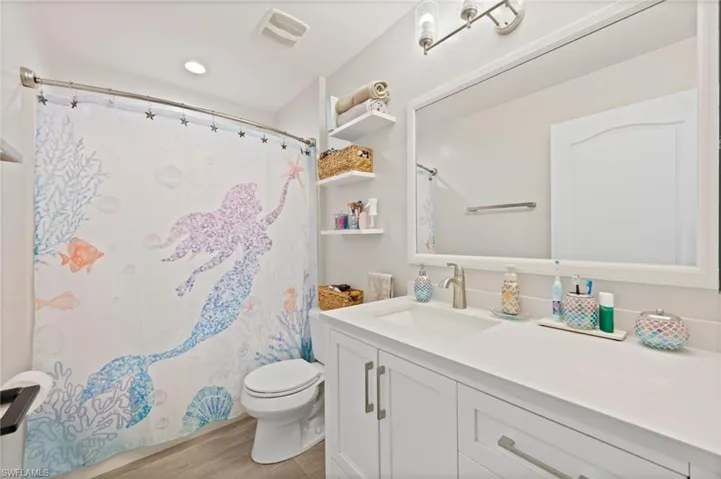 Bathroom featuring a single vanity with a white countertop, under-mount sink, and brushed nickel faucet