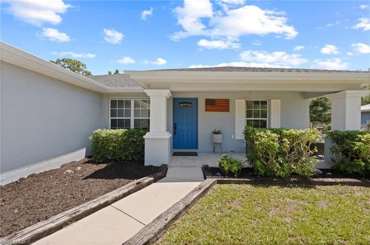 Front facade with a bright blue entry door, covered porch, and white window shutters