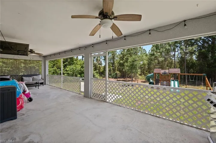 Spacious screened porch featuring a concrete floor, lattice railing, and two ceiling fans