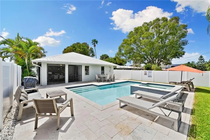 View of swimming pool with a fenced backyard, a patio, outdoor dining area, a pool with connected hot tub, and a grill