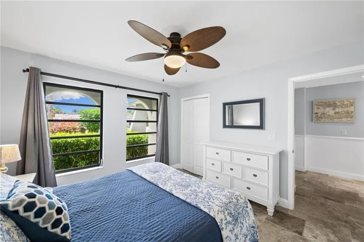 Bedroom featuring wainscoting, ceiling fan, stone tile flooring, and a closet