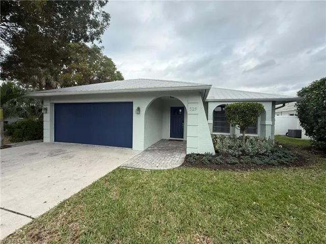Ranch-style home featuring a metal roof, driveway, a front yard, stucco siding, and an attached garage