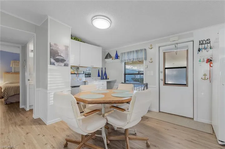 Dining area with a textured ceiling, light hardwood / wood-style floors, and crown molding