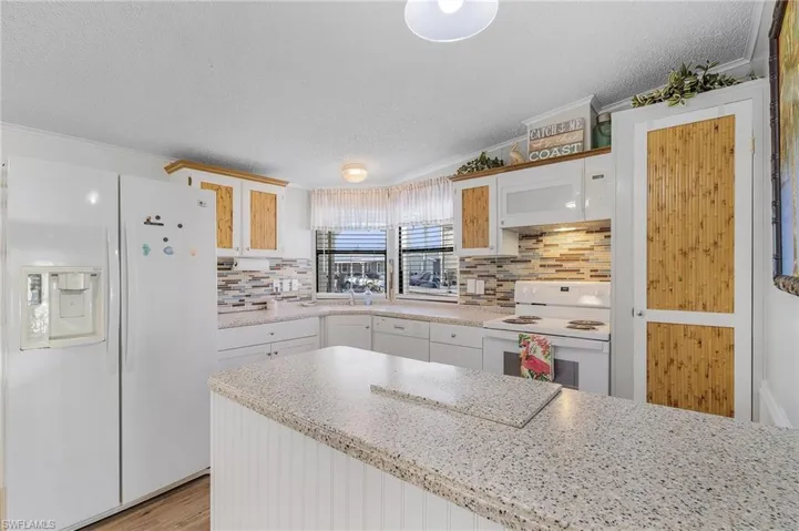 Kitchen featuring white cabinets, white appliances, and ornamental molding