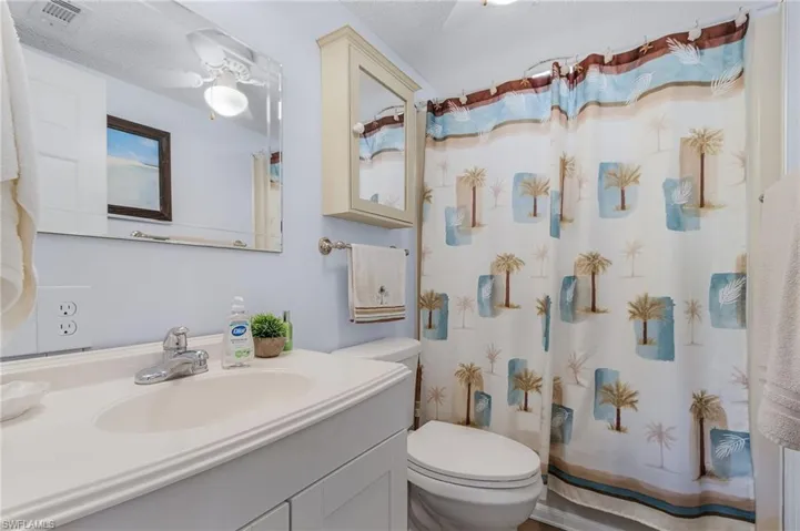 Bathroom with a shower with curtain, vanity, toilet, and a textured ceiling
