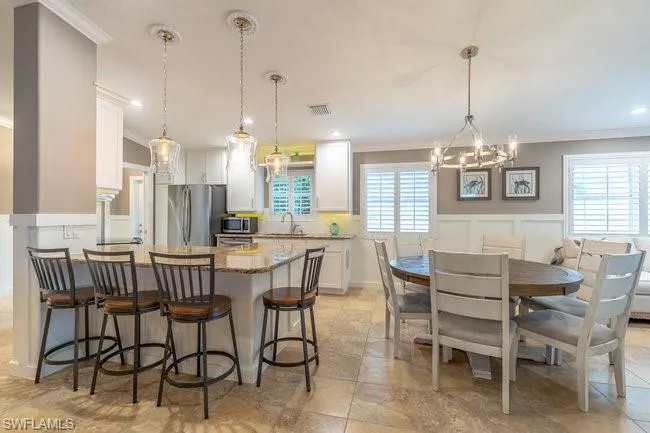 Kitchen featuring light tile patterned floors, white cabinetry, appliances with stainless steel finishes, and a wealth of natural light