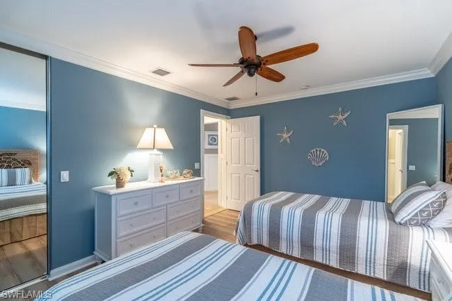 Bedroom featuring ornamental molding, wood-type flooring, and ceiling fan