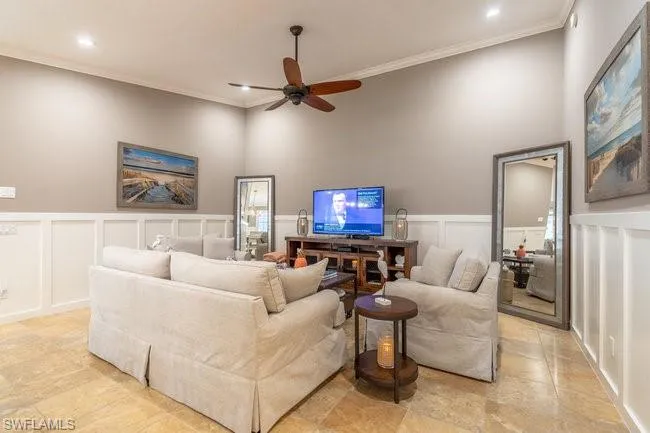 Tiled living room featuring a towering ceiling, crown molding, and ceiling fan