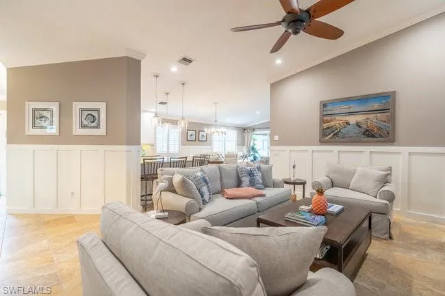 Tiled living room with ornamental molding, lofted ceiling, and ceiling fan