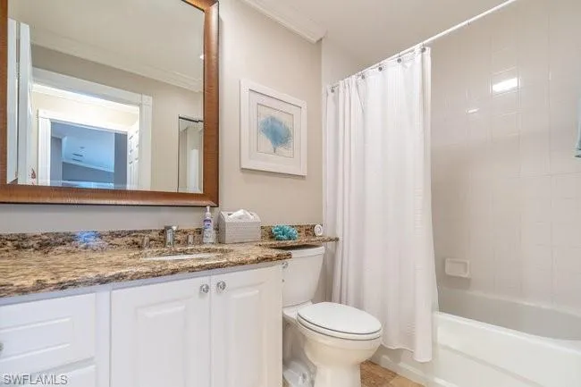 Full bathroom with vanity, shower / bath combo, crown molding, and toilet