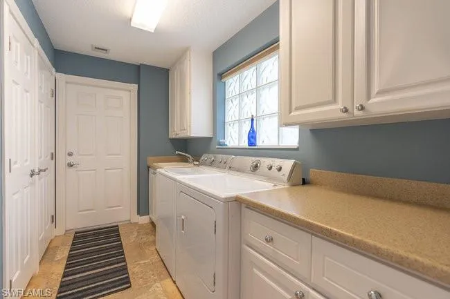 Washroom featuring washer and clothes dryer, sink, cabinets, and light tile patterned floors