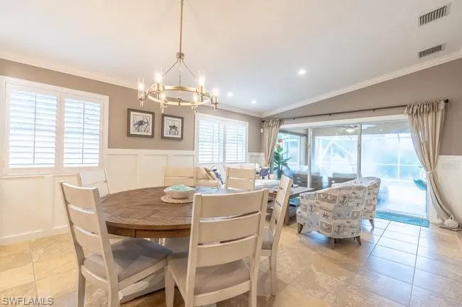 Tiled dining room with a notable chandelier, ornamental molding, and vaulted ceiling