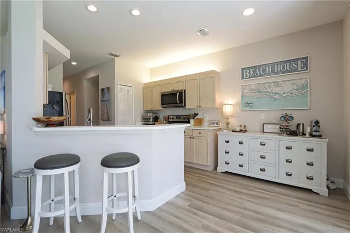 Kitchen featuring stainless steel appliances, light hardwood / wood-style flooring, a kitchen bar, and kitchen peninsula