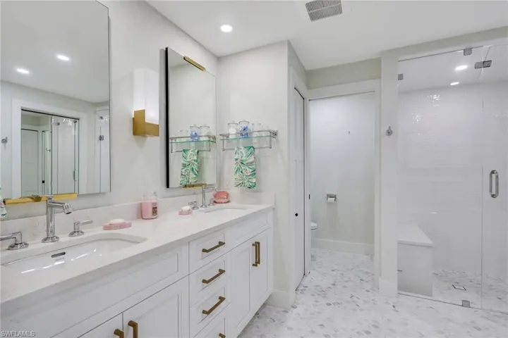 Full bath featuring a shower stall, double vanity, recessed lighting, and light floors
