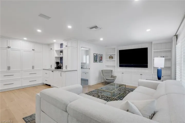 Living room featuring built in shelves, light wood-type flooring, and recessed lighting