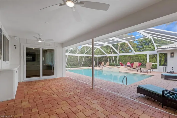 View of pool with a patio area, a sunroom, glass enclosure, and a pool with connected hot tub