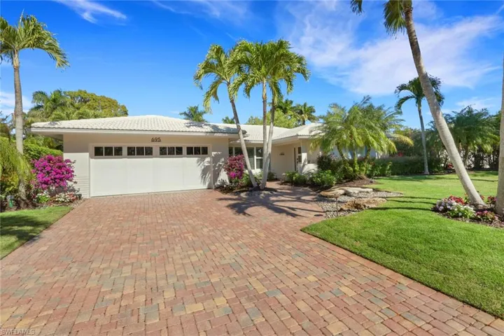 View of front of house with an attached garage, decorative driveway, a front lawn, and stucco siding