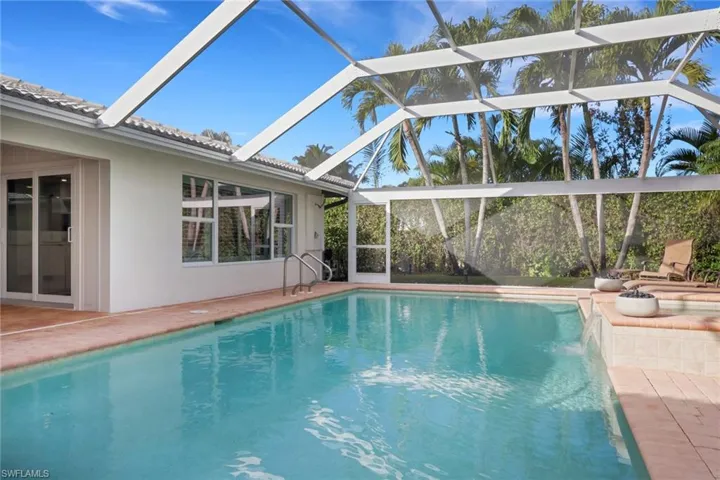 Outdoor pool featuring a sunroom, a patio, glass enclosure, and an outdoor fire pit
