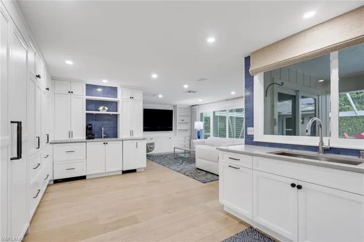 Kitchen with open floor plan, white cabinets, light wood finished floors, and open shelves