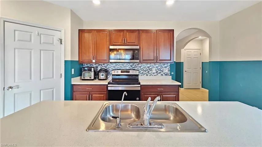 Kitchen with backsplash, light tile patterned floors, sink, and appliances with stainless steel finishes