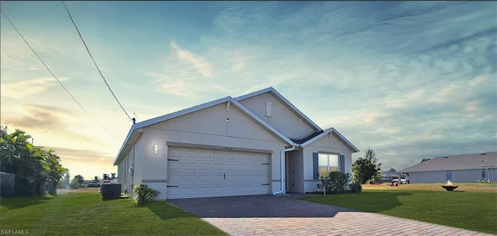 View of front facade with cooling unit, a garage, and a yard