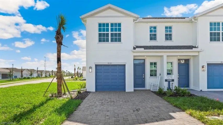 Model Home. The property features a white exterior with blue garage doors and front doors, a paved driveway, and a well-maintained lawn