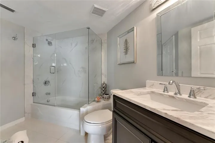 Full bathroom featuring tile floors, vanity, and bath / shower combo with glass door