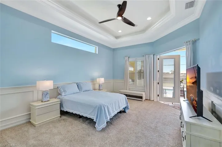 Bedroom with ornamental molding, light colored carpet, a wainscoted wall, and visible vents