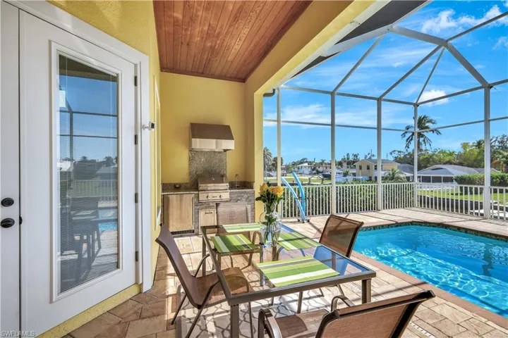 View of swimming pool featuring a fenced in pool, an outdoor kitchen, a patio area, a grill, and a lanai