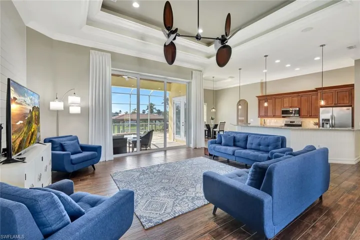Living area with a tray ceiling, dark wood finished floors, and crown molding