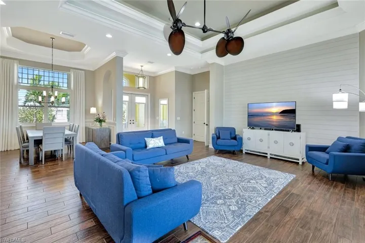 Living room with french doors, a tray ceiling, dark wood-type flooring, and crown molding