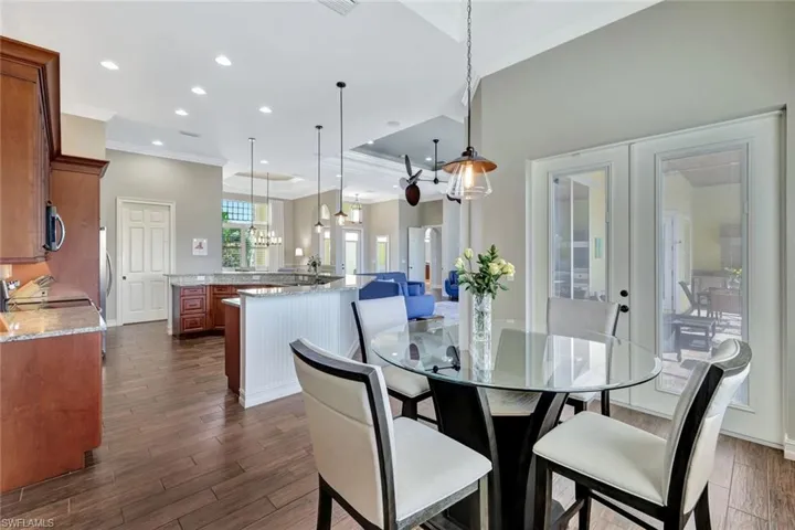 Dining space with dark wood finished floors, ornamental molding, french doors, a notable chandelier, and recessed lighting