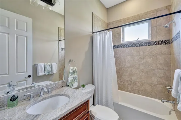 Bathroom with toilet, shower / bath combo with shower curtain, and vanity