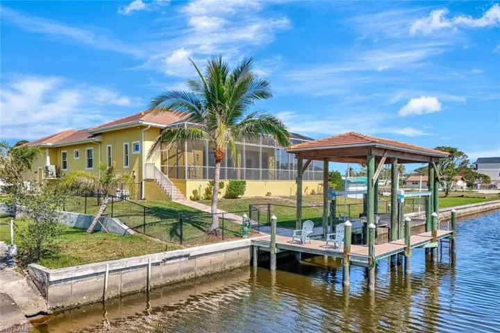 Dock area featuring boat lift, a water view, fence, stairway, and a lawn