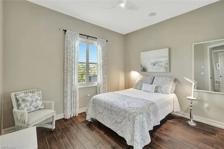 Bedroom with ceiling fan, dark wood-type flooring, and baseboards